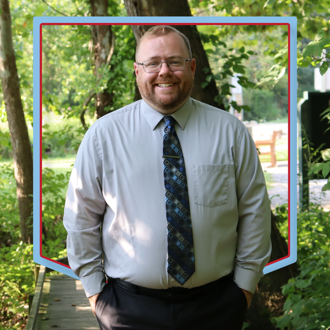 Andrew Barrand poses in front of a wooded background.